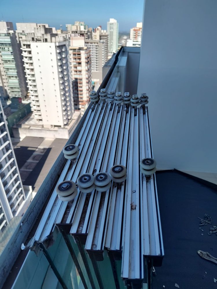 Trilhos de fechamento de varanda com roldanas novas, vista da cidade ao fundo