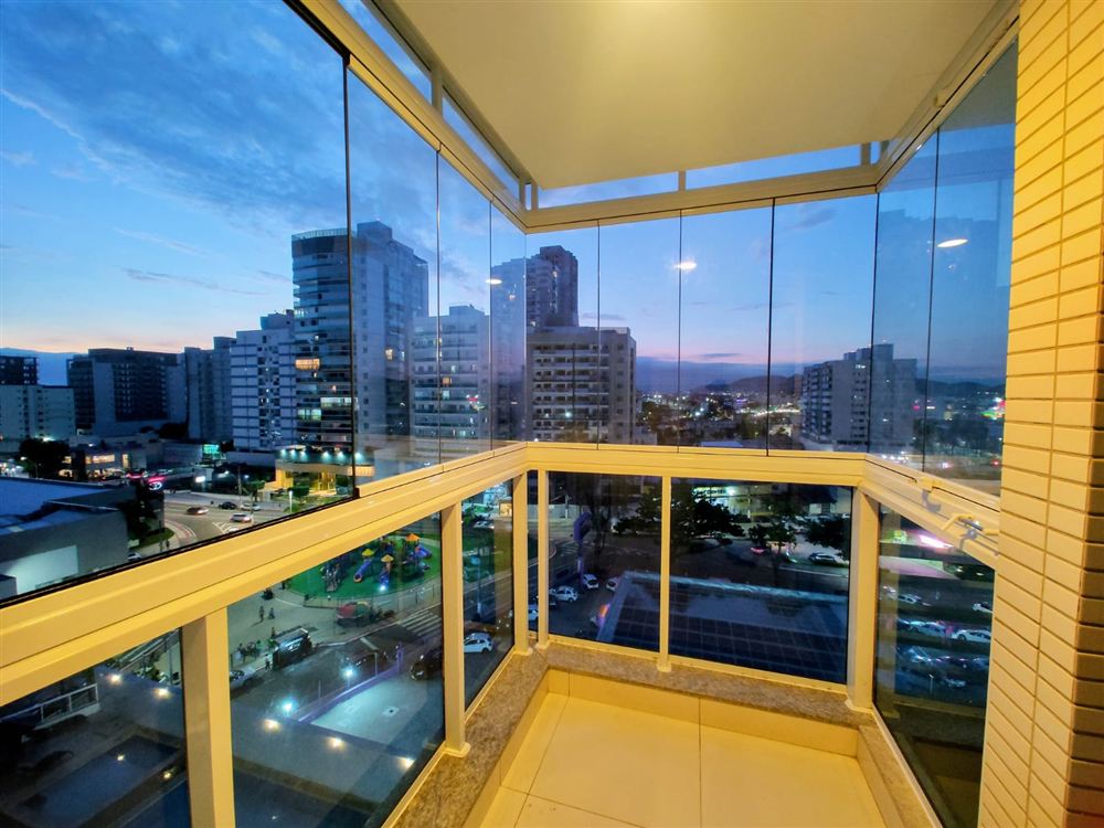 Varanda com fechamento de vidro e vista noturna da cidade
